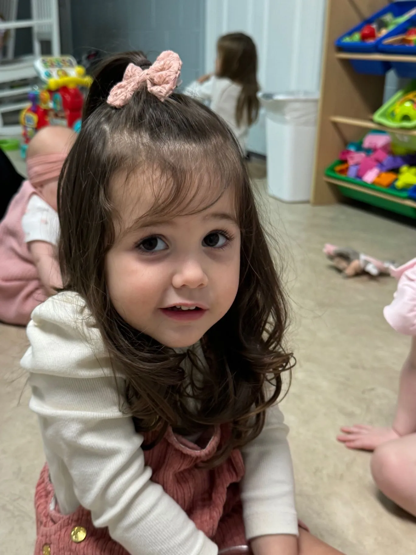 A child smiling in a Cornerstone Kids classroom with toys nearby